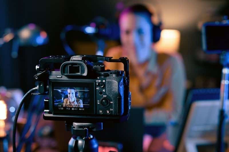 mujer grabando un vídeo de YouTube desenfocada con cámara reflex enfocada en primer plano